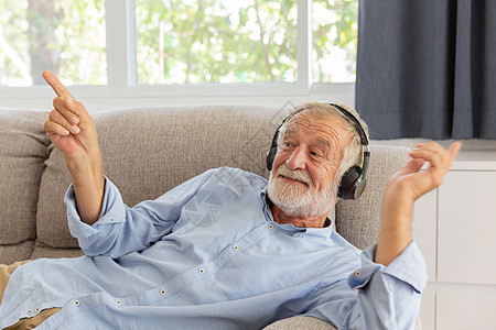 退休老人用耳机听音乐的呼声感觉哈乐趣成人潮人技术闲暇眼镜音乐播放器胡须工作室男人图片