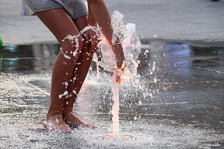赤脚女孩摸着人行道上的喷泉溪流乐趣晴天女孩衣服牛仔裤青年孩子流动跑步图片