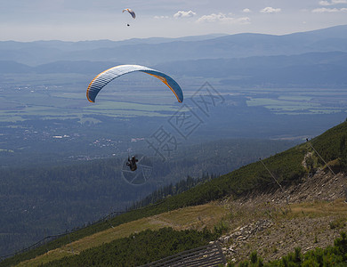 两架滑翔伞在阳光明媚的夏日飞越山谷 在斯洛伐克Tatra山上以蓝色和橙色风筝为育婴图片