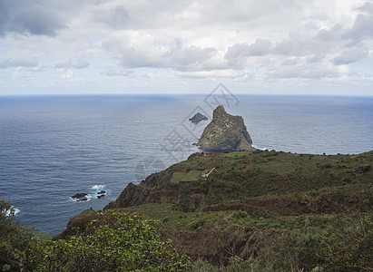 在海中的岩石上可以看到绿色的山丘和阿纳加山西班牙埃纳里夫金丝雀岛中戏剧性的蓝色天空白云旅行公园火山戏剧性房子路线石头侵蚀踪迹农村图片