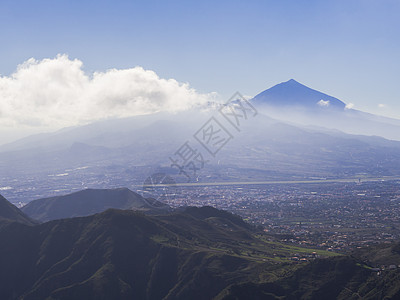 皮科德尔泰德火山蓝色山顶云中西班牙最高山峰 可欣赏拉奥罗塔瓦市和绿色山丘 特内里费加那利岛 蓝天背景图片