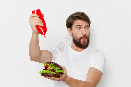 一个男人拿着一罐番茄酱 手里拿着一个汉堡包图片