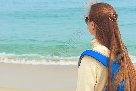 女孩在海滩上的女孩游客海洋海浪背包太阳海岸女士反射旅行蓝色图片