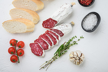 白表面的西班牙沙尔西翁切片 顶视图上方有帕尼尼和草药食物塔帕冷盘猪肉火腿白色熏制小吃香肠图片