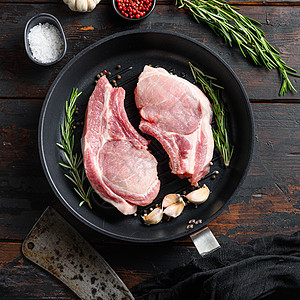 烧烤炉锅里骨头上的生猪肉牛排 用屠刀或切刀和大刀在老旧的黑木板上做烤架顶端视图方图片