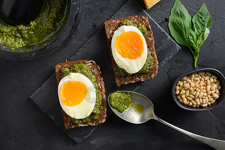 土制鸡蛋番尼面包 意大利早餐上加绿色烤肉卷银勺 黑石混凝土桌面的绿虫子成分 紧闭地表顶视图图片