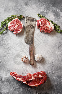 各种牛肉 Delmonico 牛排或 Ribeye 牛排 Bone-In 用美国切肉刀在灰色石桌石板上切割的夹眼卷切顶视图普通面图片