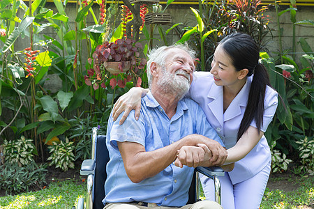 护士照顾一名年长的男性 在他花园里坐在轮椅上照顾者讲话治疗退休女性病人人士公园快乐房子图片