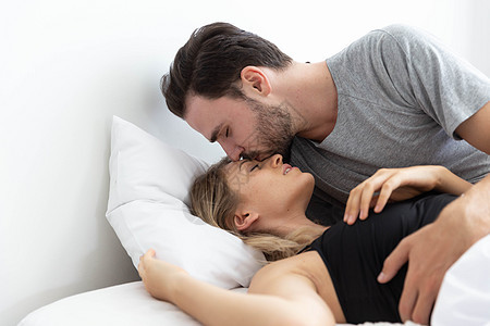 在床上的白种夫妇 和男人亲吻女人在她的额头上图片