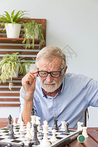 在家玩象棋的老年退休男子 在家中竞赛竞争白色思考专注男人闲暇眼镜棋盘游戏图片