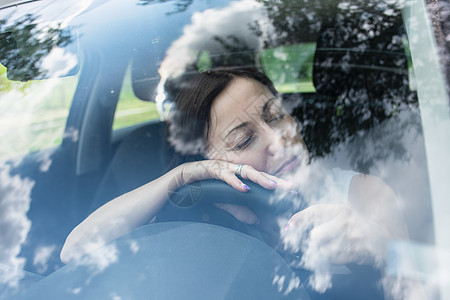 年轻的女司机驾驶着她的汽车 非常疲倦 在潜在的危险情况下开车时睡着了 睡在方向盘上 驾驶安全理念图片