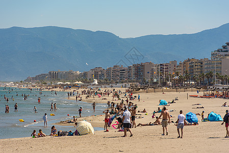 海滩上的人 在旅游镇Canet en R的阳光日茅草房子蓝色旅行晴天支撑橙子沙丘反射假期图片