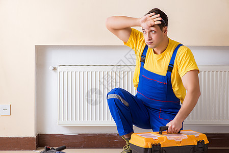 修理暖气板的年轻修理工承包商扳手加热器工具工人空调电工男人散热器技术员房间图片