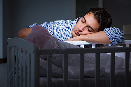 年青父亲在照顾新生儿时睡着的年轻父亲午睡男生睡眠房间苗圃父母儿子母性护理幸福图片