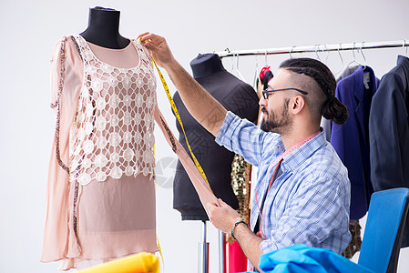 在新设计讲习班上工作的男裁缝手工业作坊设计师男性材料磁带衣服人体裙子服装图片