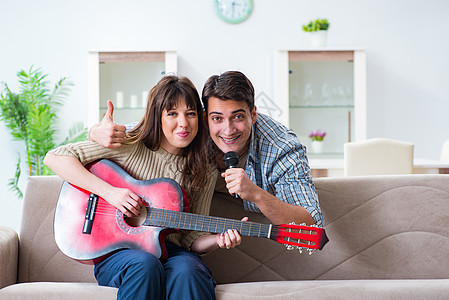 年轻家庭在家里唱歌和演奏音乐演员爱好闲暇居住音乐家享受房间嗓音沙发拇指图片