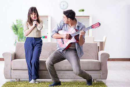 年轻家庭在家里唱歌和演奏音乐闲暇麦克风妻子记录艺术派对房间乐趣嗓音岩石图片