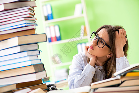 年轻女学生准备参加许多书本的考试教科书困惑研究学校课堂宿舍知识训练女士图书馆图片