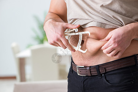 体脂肪和卡利帕的测量人卡尺痛苦肚子身体饮食躯干示范统治者便便测试员背景图片