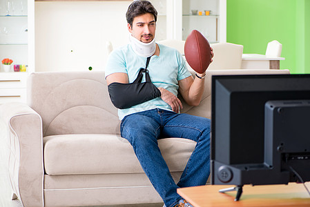 在电视上观看美式足球比赛时 脖子和手臂受伤的男子保险鞭打沙发治疗运动疼痛颈椎病保健绷带观众图片