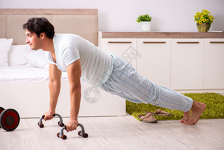 年轻人在卧室做晨间例行活动俯卧撑房子娱乐睡衣训练男性男人饮食重量健身房图片