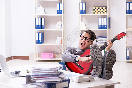 年轻英俊的商务人士 在办公室弹吉他乐趣歌手情绪吉他乐器商业享受职场音乐家工人图片