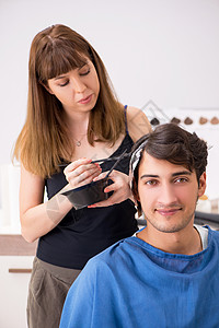 年青男子看女理发师顾客画笔男性发型师服务深色金发造型师男人造型图片