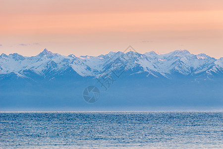 伊塞克湖湖 雪峰山和清晨粉红色天空图片