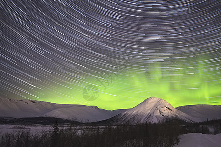 夜空中星轨和白云中绿色北极光的星际轨迹图片