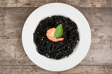 黑意大利面 有虾和木桌上的巴锡盘子美食海鲜面条食物营养黑色对虾饮食图片
