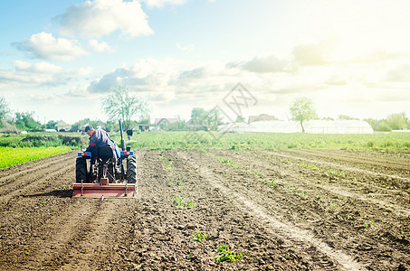 农田拖拉机拖拉机上的农民用铣床松土 准备种植土壤的第一阶段 疏松地表 开垦土地 使用农业机械 农业 农业 犁田背景