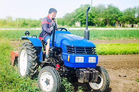 一位农民在农田里开着拖拉机工作 疏松地表 耕种土地 农业 农业 农业机械设备使用简化和加快工作图片