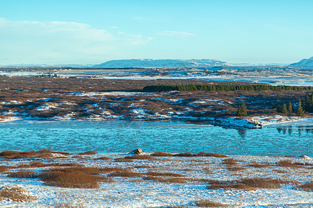 冰岛平原的河流 河岸上满是积雪 冬季风景 空旷的空间冰川环境蓝色溪流日落全景地标场景太阳旅行图片