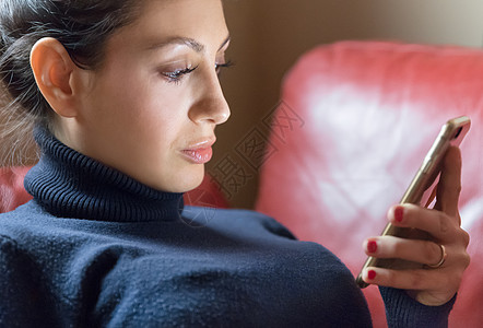 在红沙发上使用智能手机的年轻天主教女青年图片