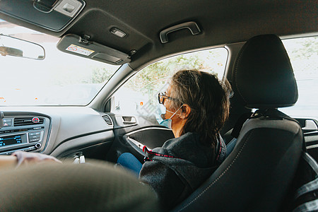 在汽车前海戴面罩的老女人女性照顾者护理收容所病人长老流感保健祖母老年图片