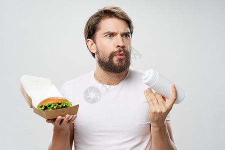 手里拿着金山的男人 快速食物饮食白T恤图片