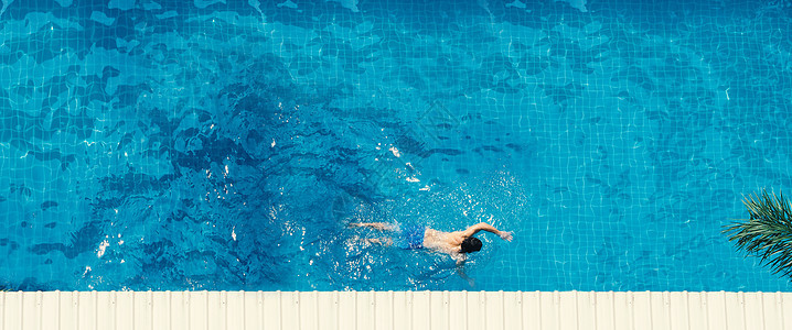 青年男子游泳的泳池顶视图角度闲暇阳光高架泳装棕褐色身体女性日光浴假期床垫图片