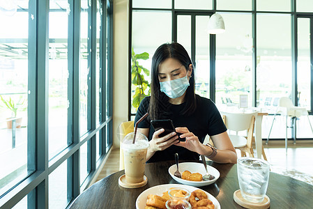 一位亚洲美女必须戴蓝面罩 为准备女孩杯子桌子早餐食物椅子咖啡餐厅面具牛奶图片