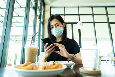 一位亚洲美女必须戴蓝面罩 为准备面具衬衫桌子牛奶食物女孩杯子早餐椅子咖啡店图片