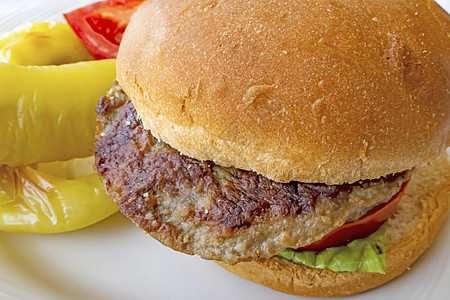 餐盘上加青辣椒和西红柿的汉堡汉堡包芝麻面包牛肉包子烧烤薯条小吃汉堡芝士食物图片