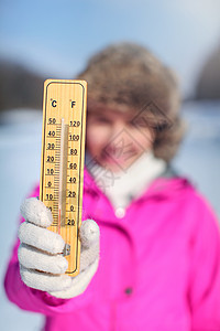 穿着粉红色运动夹克的年轻女子 手持木制温度计图片