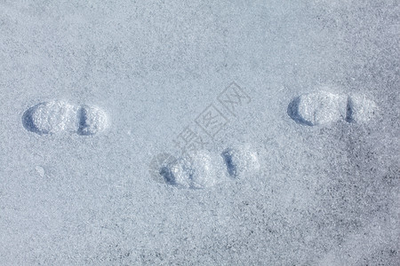 在阳光明媚的天气下 冰雪中三个足迹的顶端景色图片
