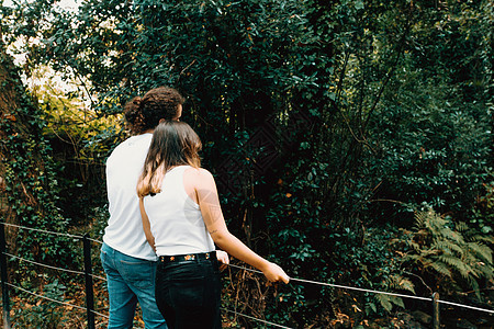 年轻夫妇在森林的一条河上桥上休息图片
