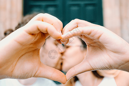 年轻情侣用手做心脏符号 在背景上亲吻对方 并用手做心象征男朋友成人女孩手势男人手指情感夫妻女士女朋友图片