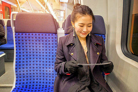 年轻女子坐在火车上看门票时 正在旅行图片