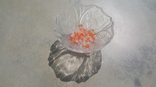 在玻璃碗中闪光 透明 橙色的晶珠或宝石玛瑙琥珀珠宝作坊工作室反射吊坠配饰手工宏观图片