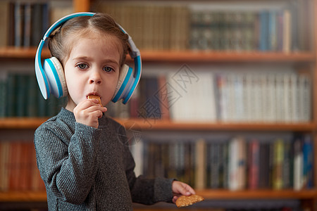 穿着白色大耳机的白人可爱小女孩 在内地用书架的背景来听音乐 笑声打碟机女孩微笑喜悦女性快乐童年乐趣技术歌曲图片