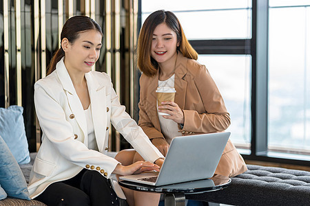 两位亚洲女商务人士在现代会议室 办公室或工作空间 咖啡休息时间 合作伙伴和同事概念中通过技术笔记本电脑与合作伙伴业务合作图片