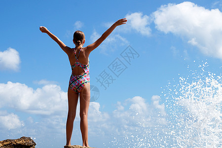 少女站在海边石头上举起的手之上海景青少年旅行自由女孩海洋风景天空青年岩石图片