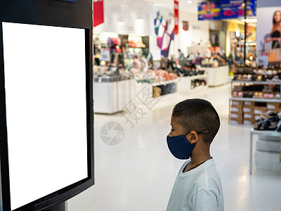 一名戴面罩的男孩在商场看空广告牌图片